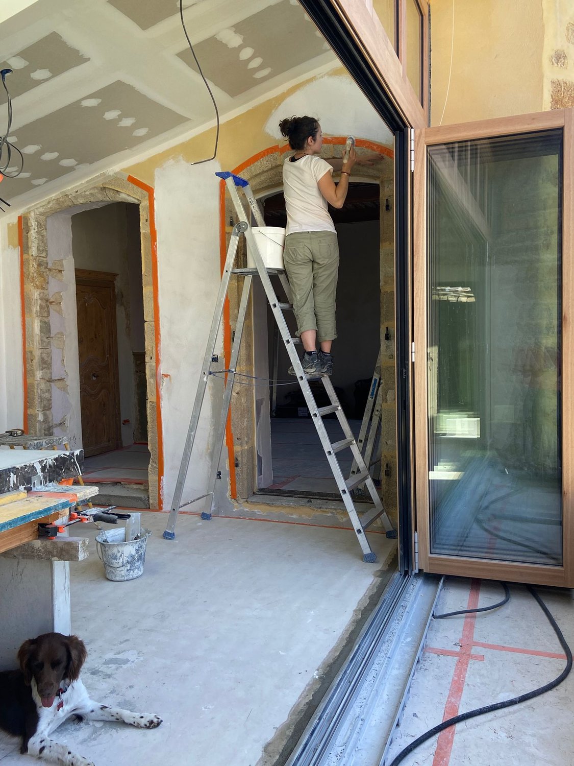 Lucile Wenger sur un escabeau, finition à la chaux autour d'une arche en pierre