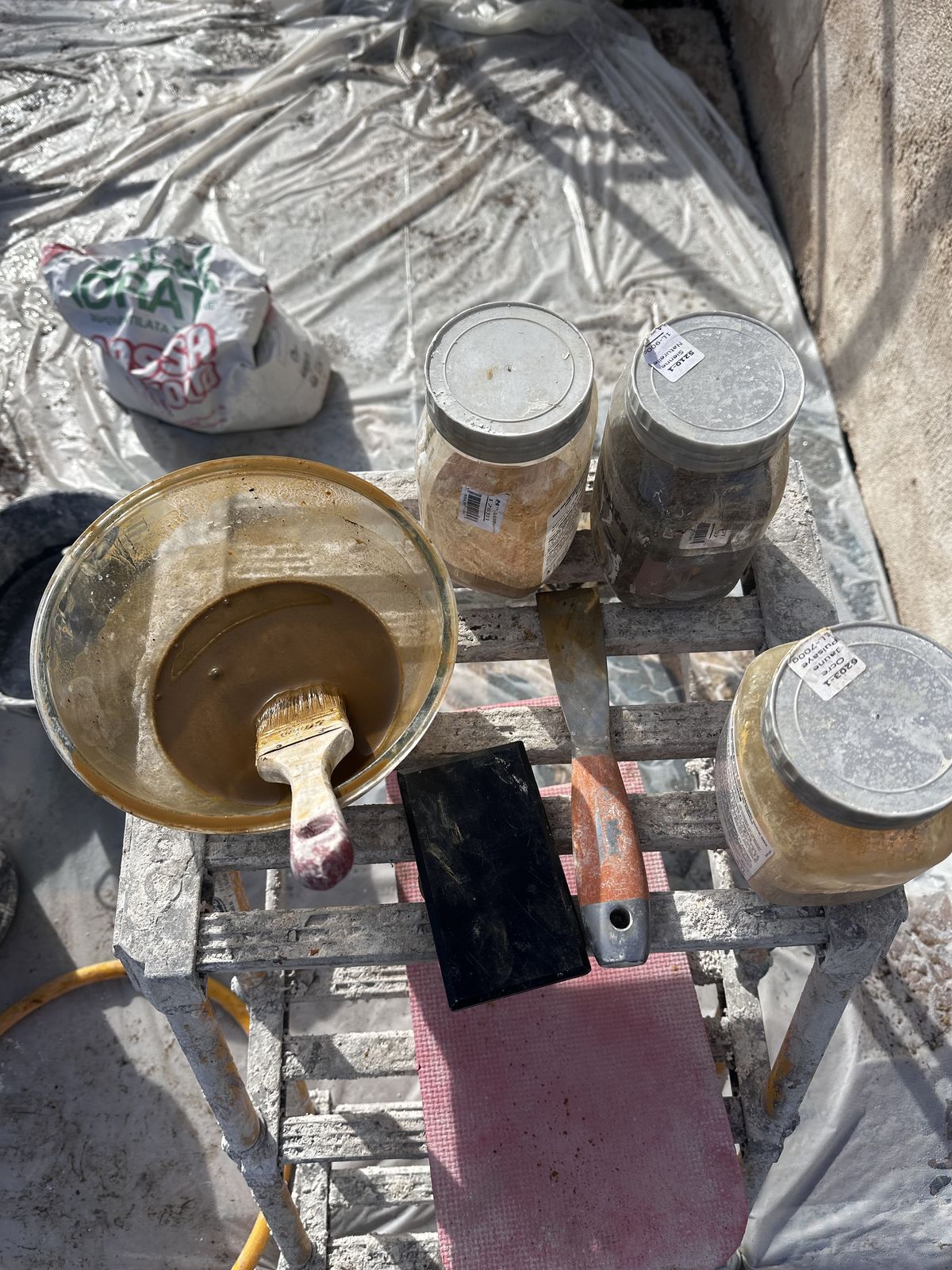 Bassine de lait de chaux avec sa brosse, taloche et pots de pigments naturels sur le chantier