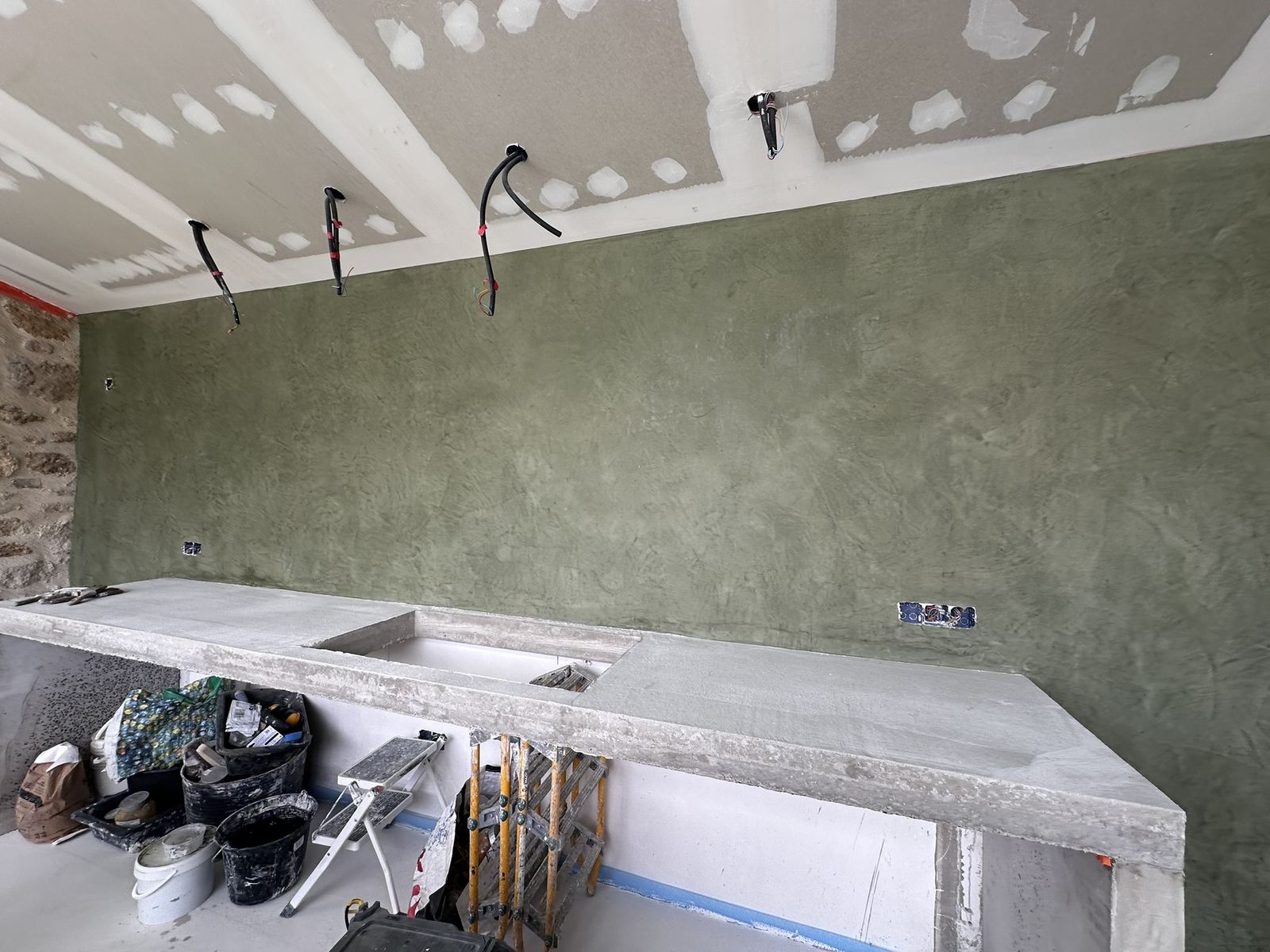 Mur de cuisine en tadelakt vert au-dessus d'un plan de travail