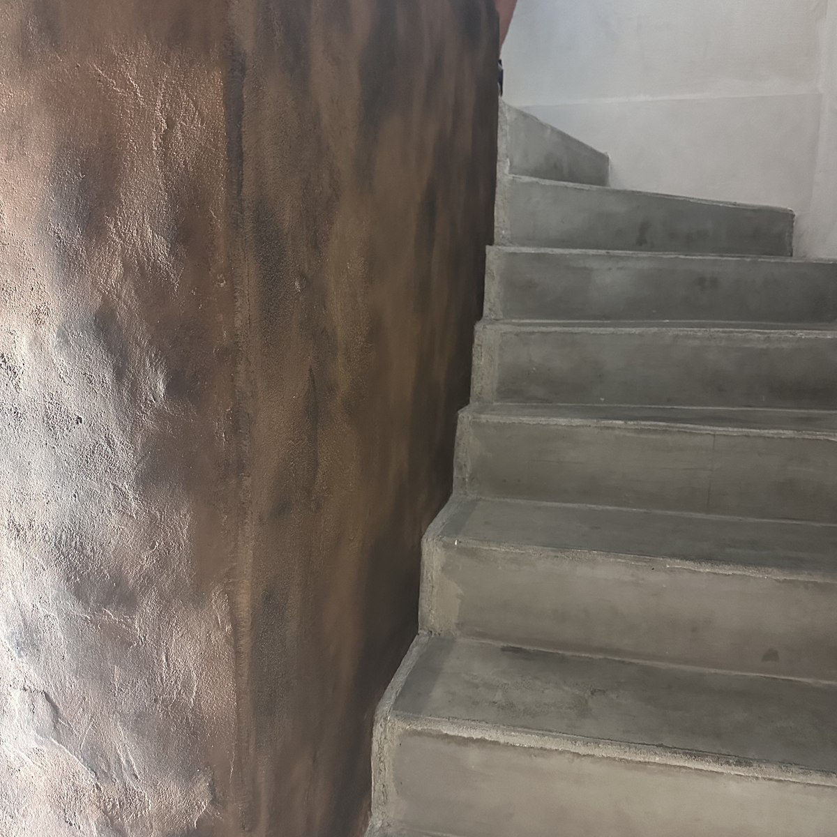 Pilier en terre texturée le long d'un escalier en béton ciré